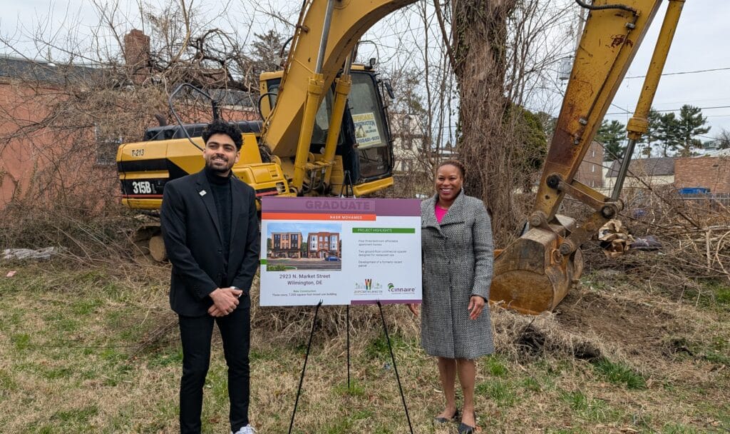 Nasr and Dionna flank poster of new development , with construction equipment in background